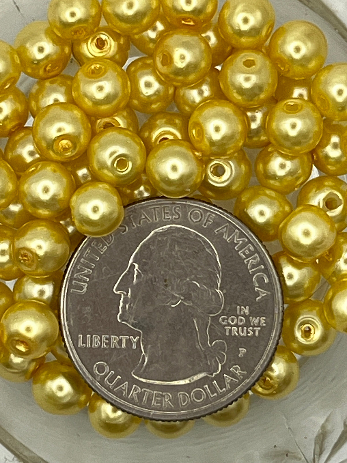 6mm yellow glass pearl beads shown next to a US quarter for size comparison.