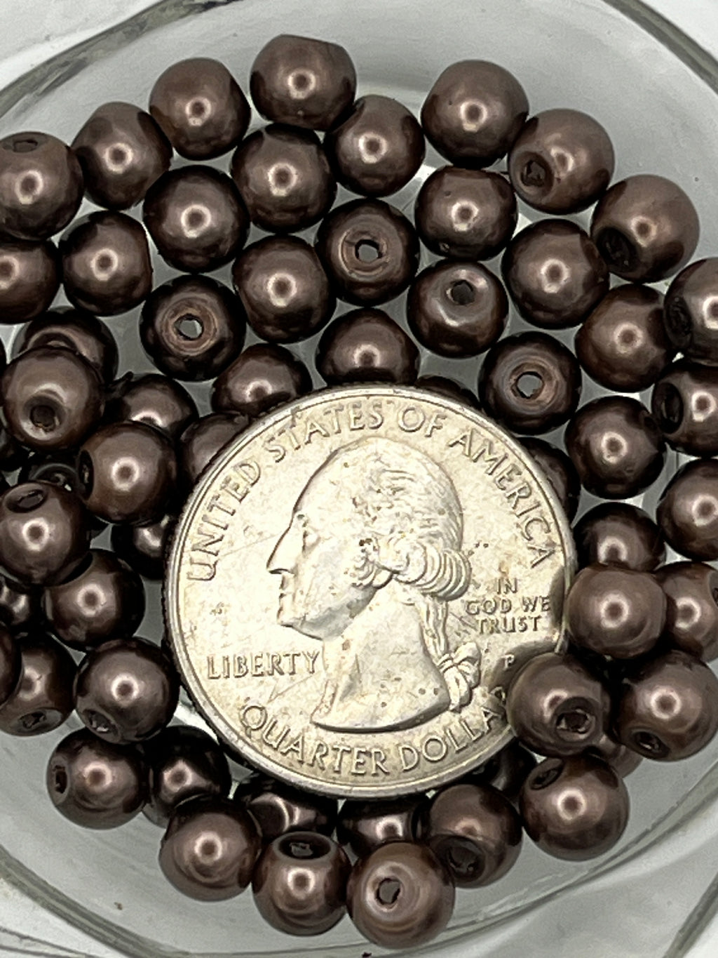 Tan 6mm glass pearl beads with a quarter for scale.