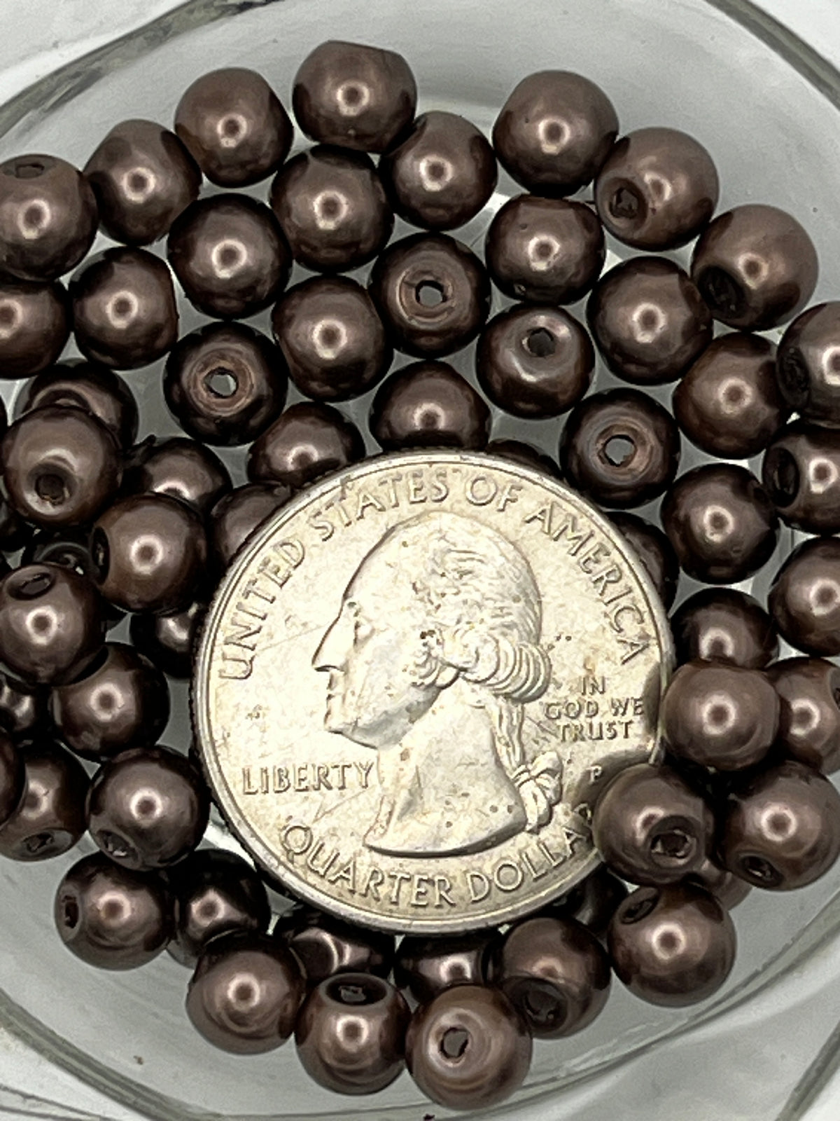 Tan 6mm glass pearl beads with a quarter for scale.