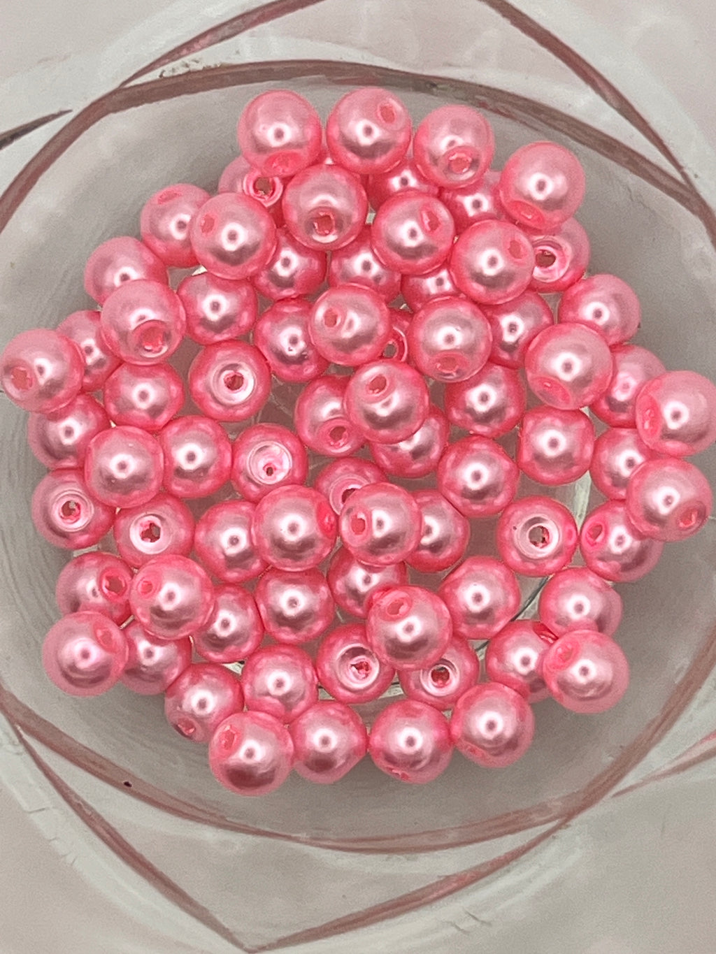 A cluster of 6mm hot pink glass pearl beads with 1mm holes for jewelry and craft making.