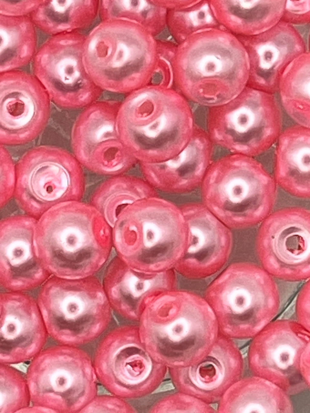 Close-up of 6mm hot pink glass pearl beads for jewelry and craft making.