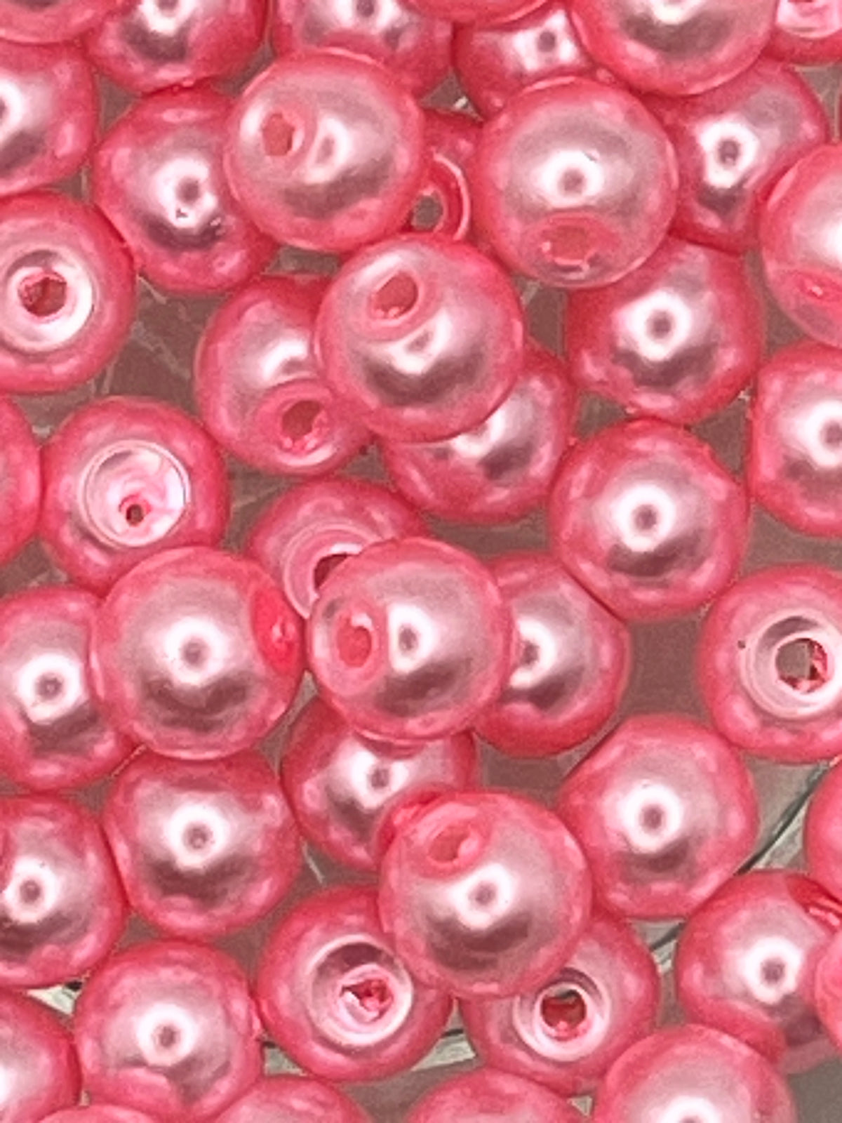 Close-up of 6mm hot pink glass pearl beads for jewelry and craft making.