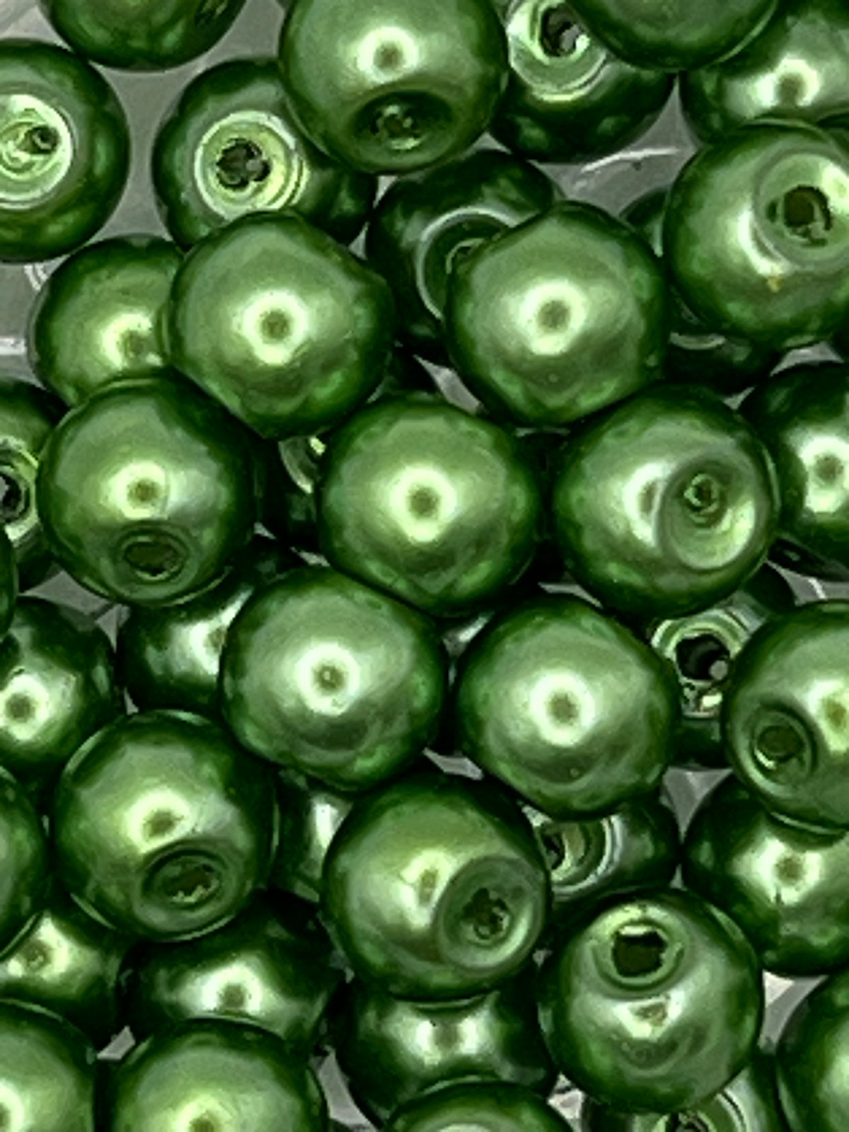 Close-up of 6mm green glass pearl beads with a glossy finish and 1mm holes.