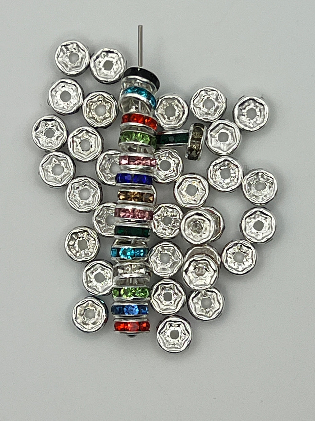 A stack of 6mm silver-toned spacer beads with colorful glass rhinestones and loose silver spacers.