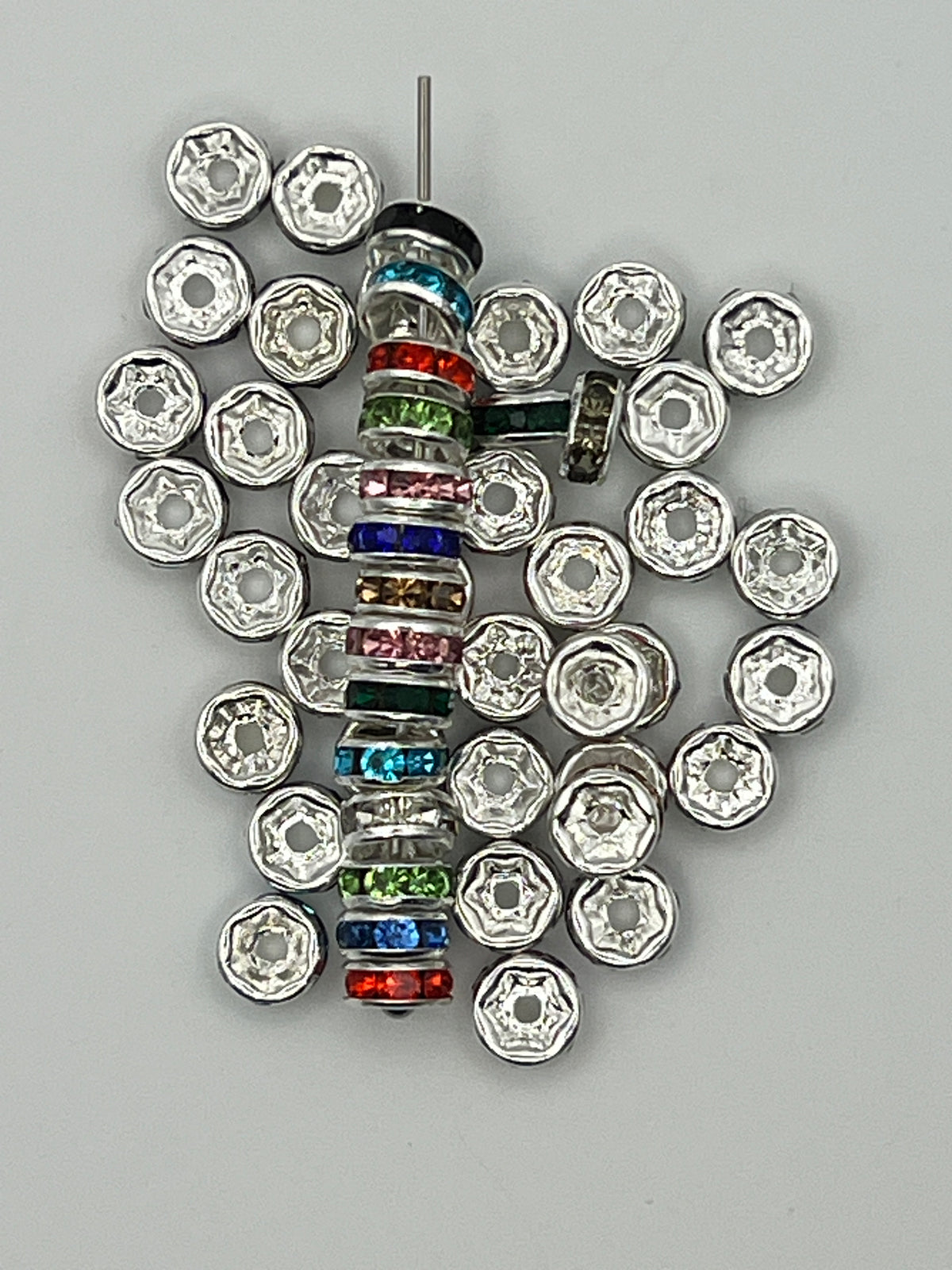 A stack of 6mm silver-toned spacer beads with colorful glass rhinestones and loose silver spacers.