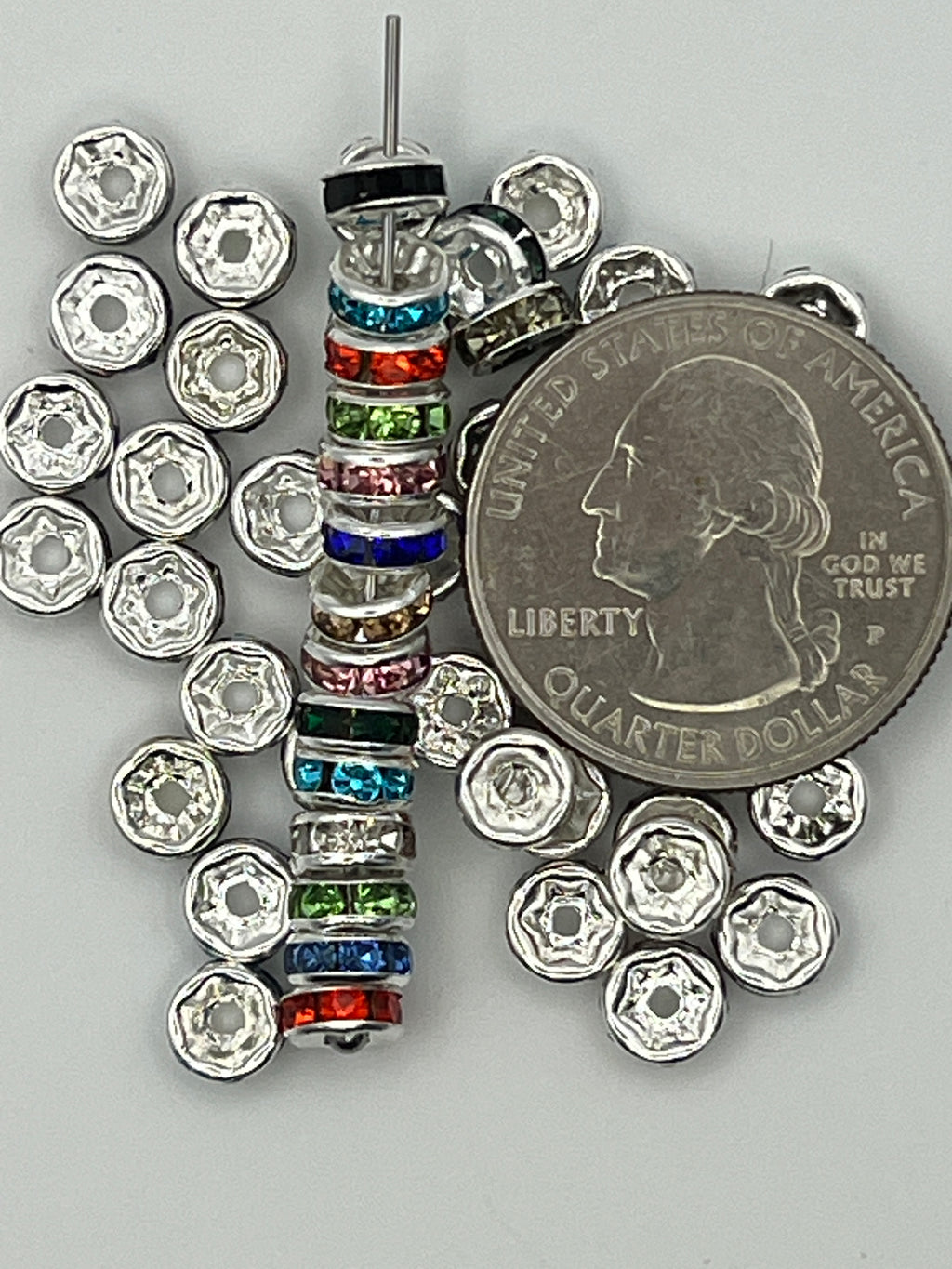 A stack of colorful rhinestone spacer beads next to a US quarter.