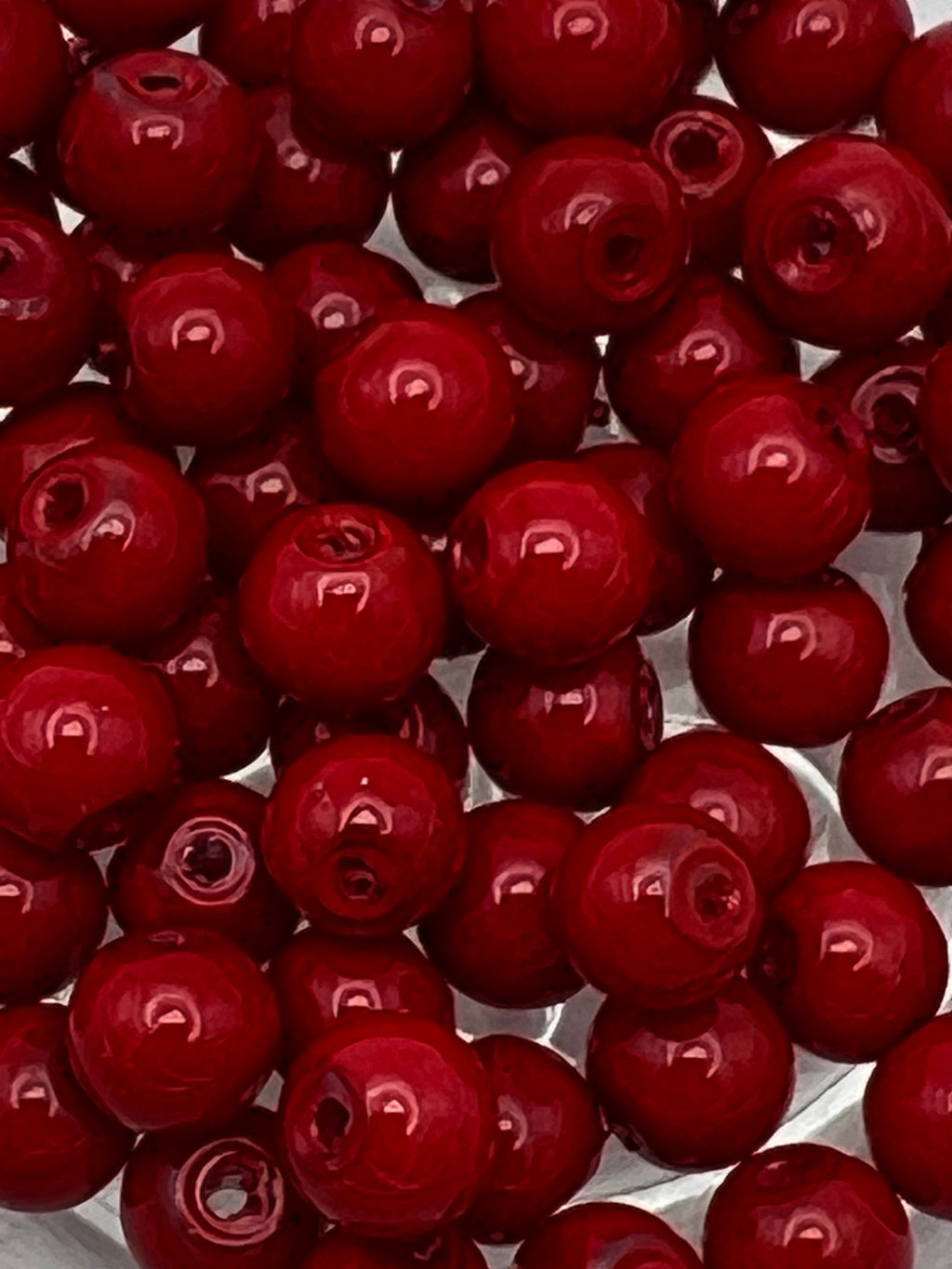 Round 6mm red glass pearl beads with a subtle sheen, shown in a close-up, top-down view.
