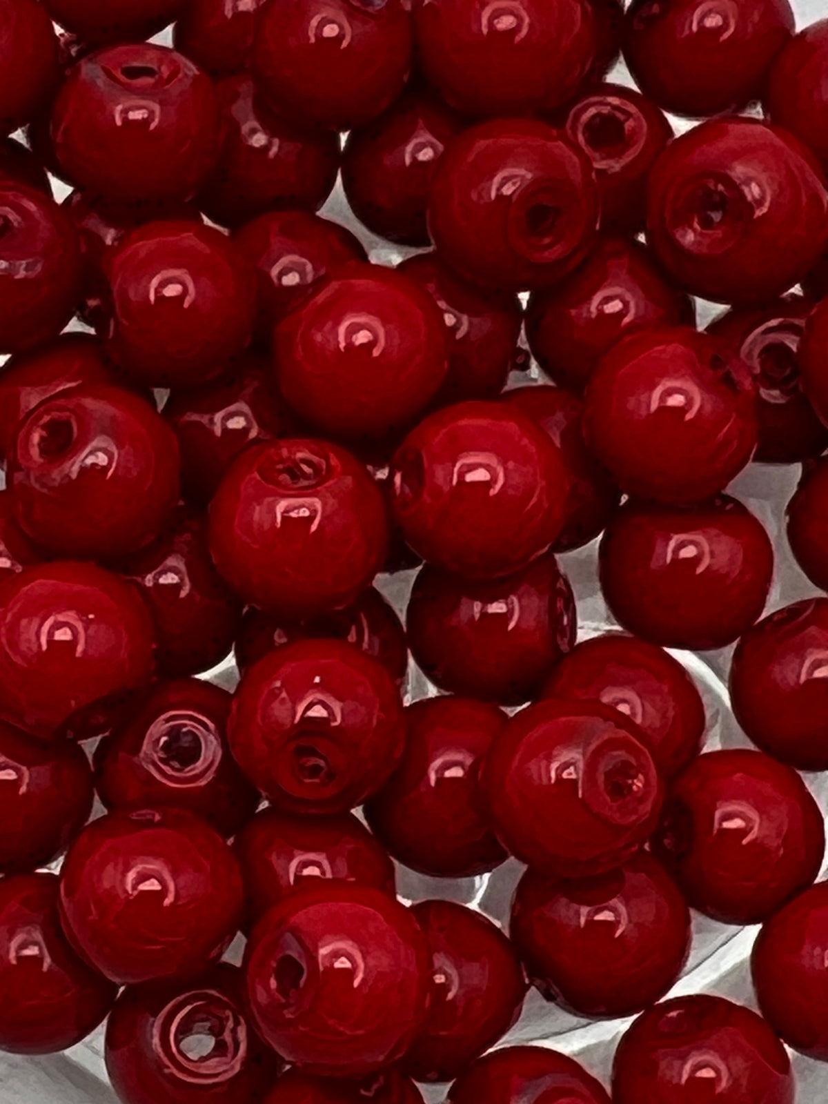 Round 6mm red glass pearl beads with a subtle sheen, shown in a close-up, top-down view.