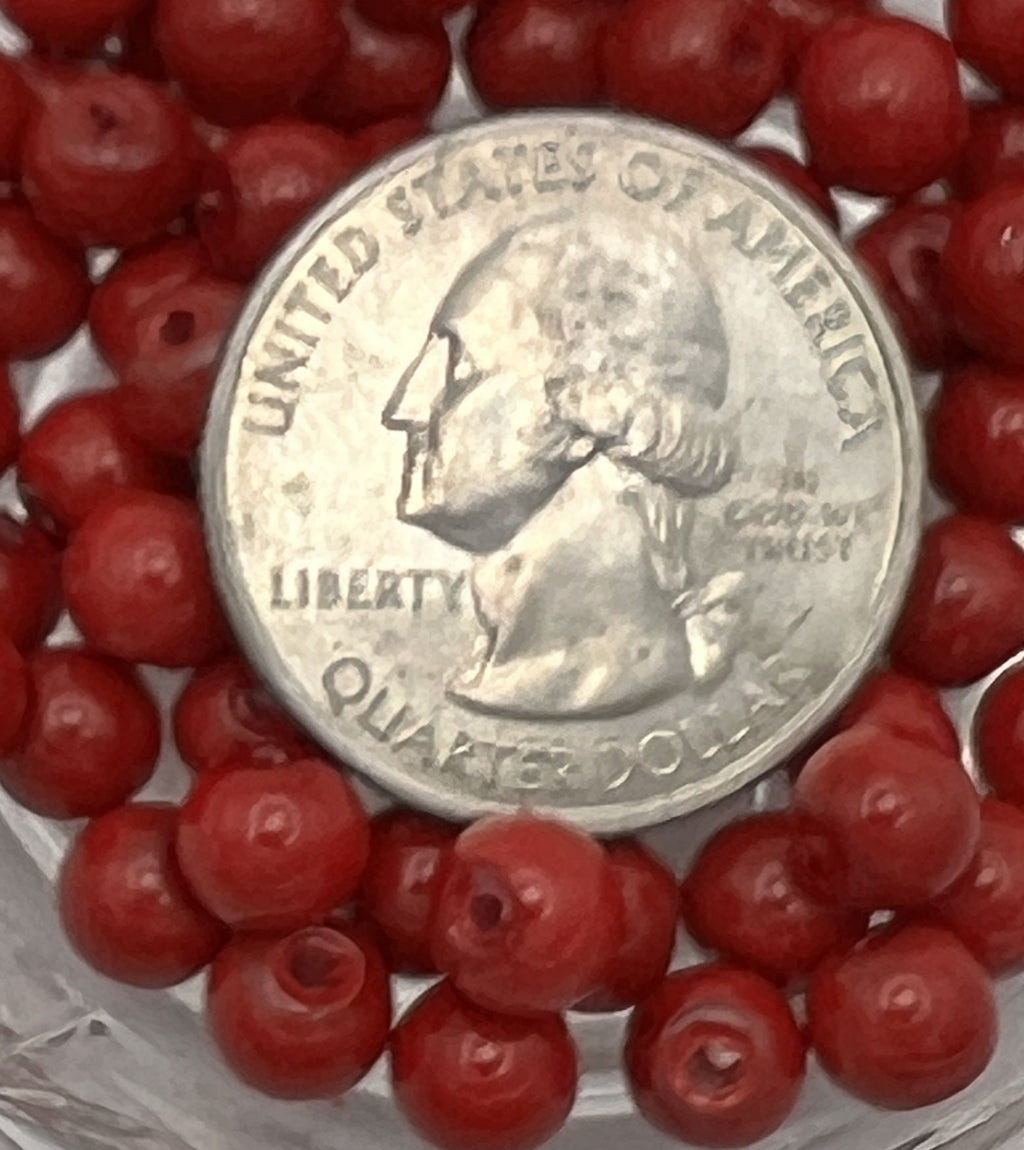 A quarter coin surrounded by small, round, red glass pearl beads.