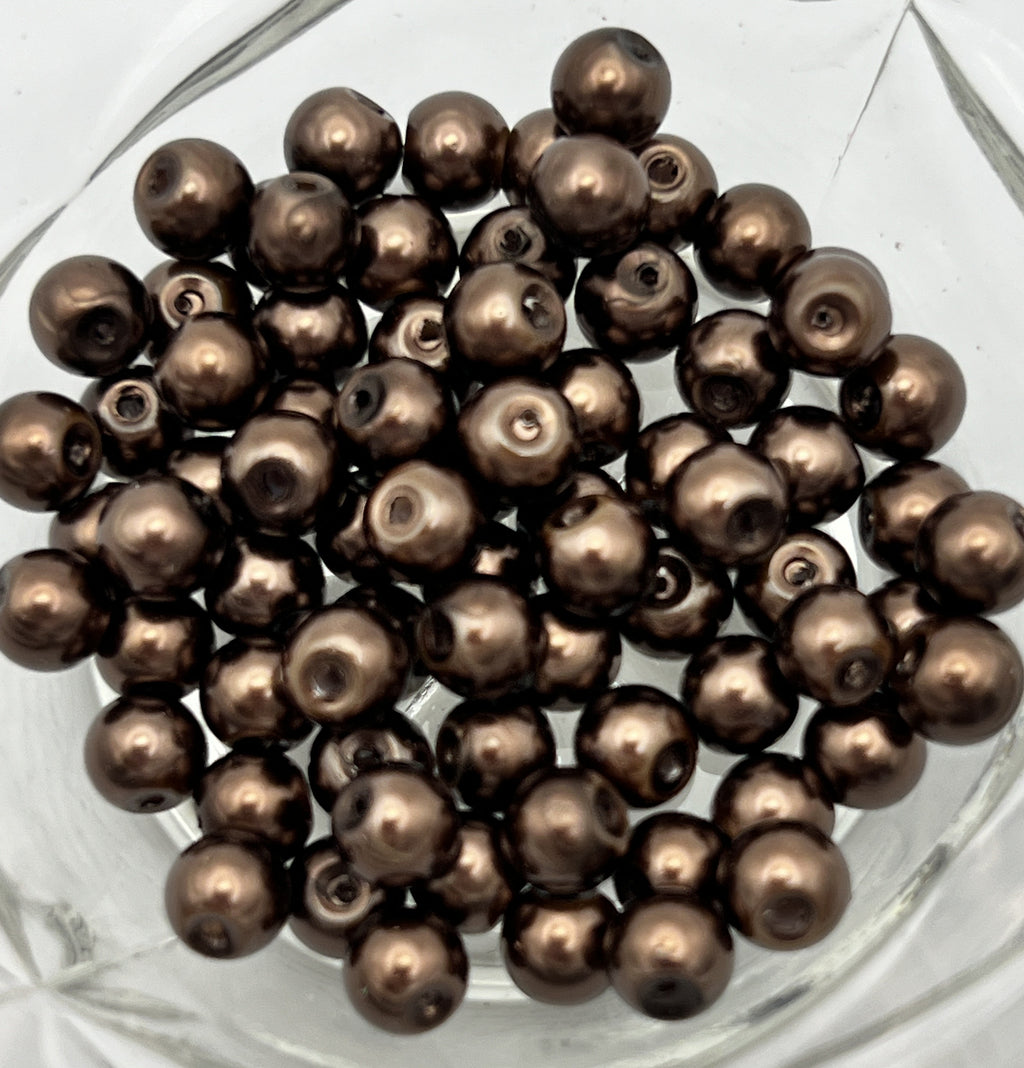 A pile of 6mm saddle brown glass pearl beads with a 1mm hole.
