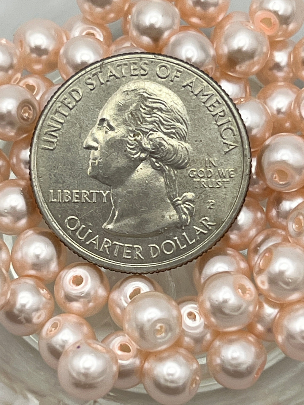 Peach puff glass pearl beads with a quarter for size reference.