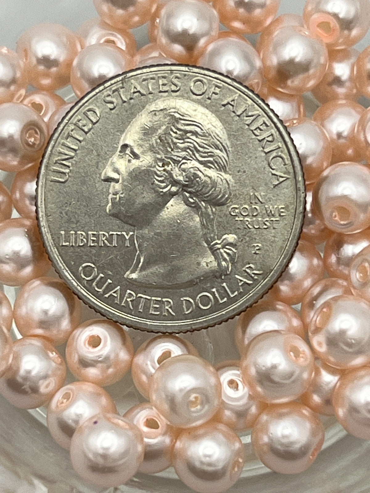 Peach puff glass pearl beads with a quarter for size reference.