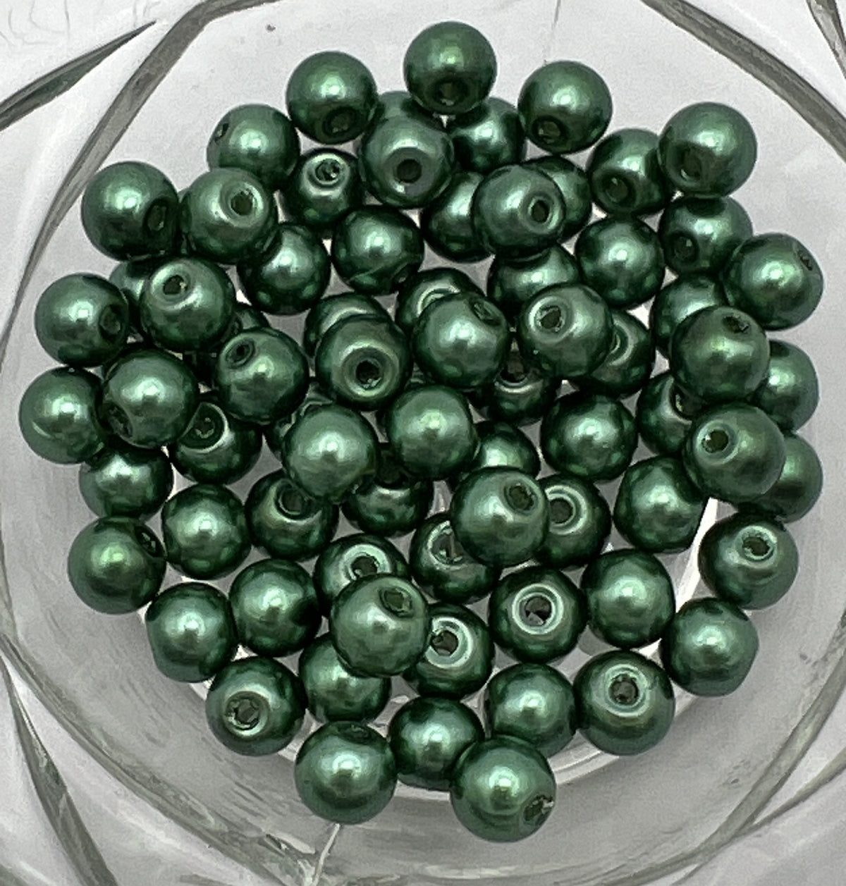 A pile of 6mm dark green glass pearl beads with a 1mm hole.