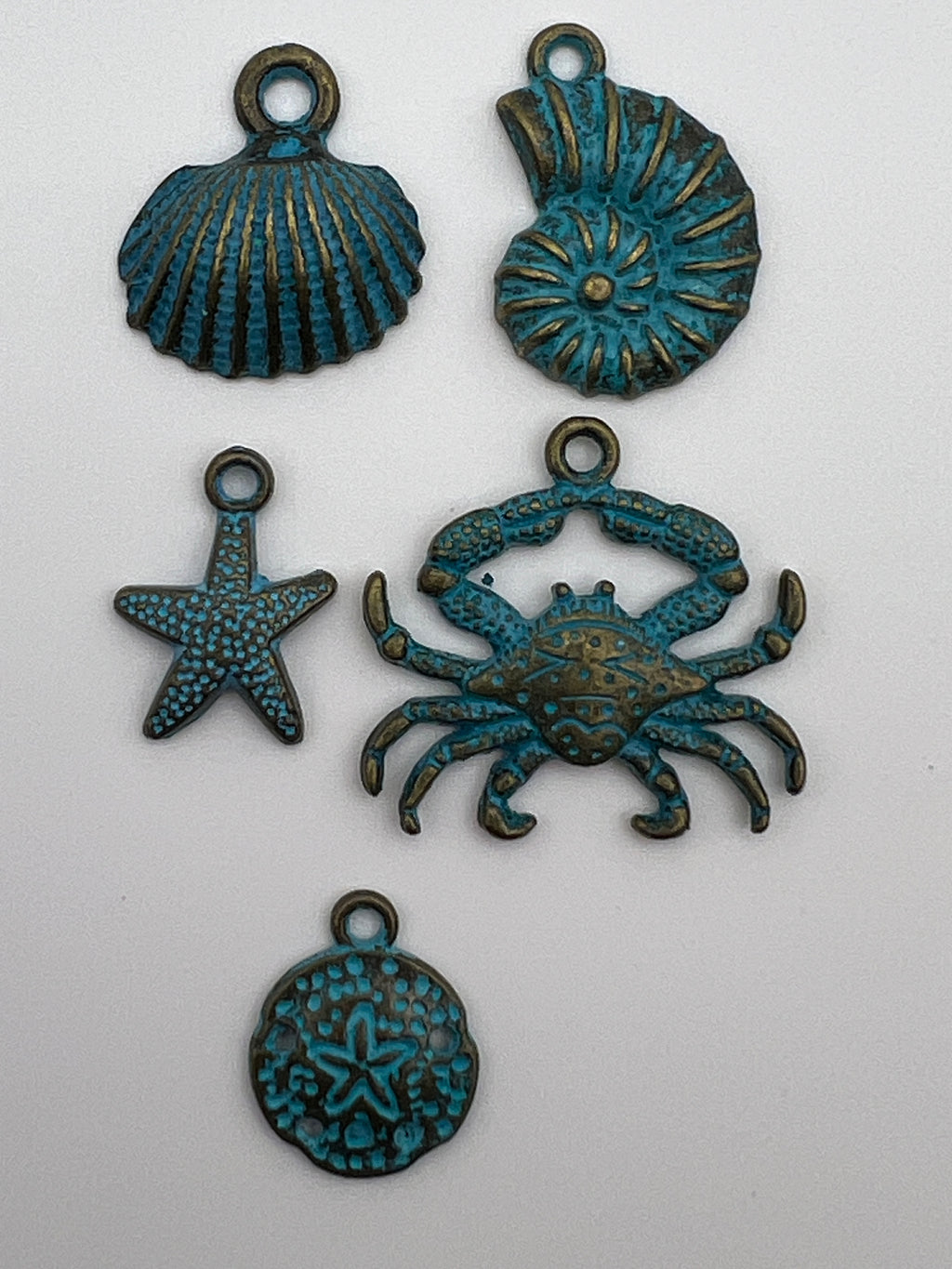 Five ocean-themed Tibetan style pendants in patina bronze, including a crab, starfish, and shells.