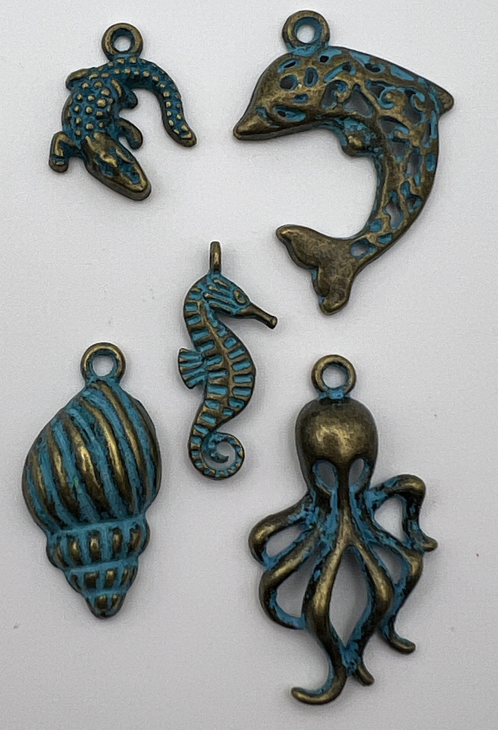 Five antique bronze Tibetan style ocean animal pendants with a blue patina finish on white background