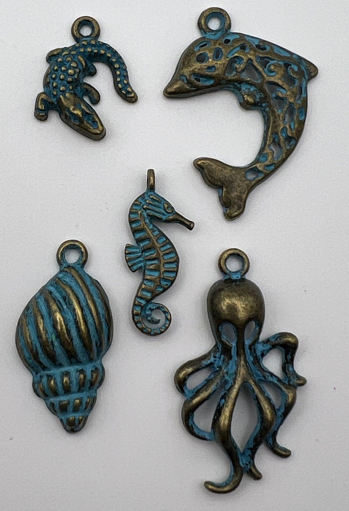Five antique bronze Tibetan style ocean animal pendants with a blue patina finish on white background