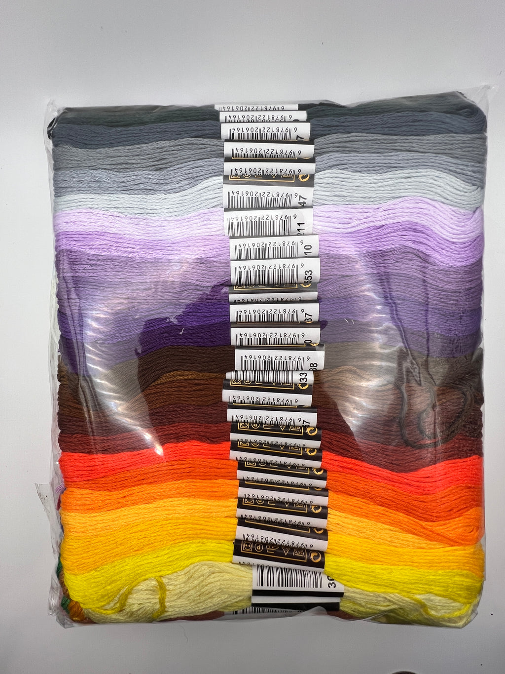 A pack of 100 mixed color embroidery thread skeins arranged in a rainbow gradient.