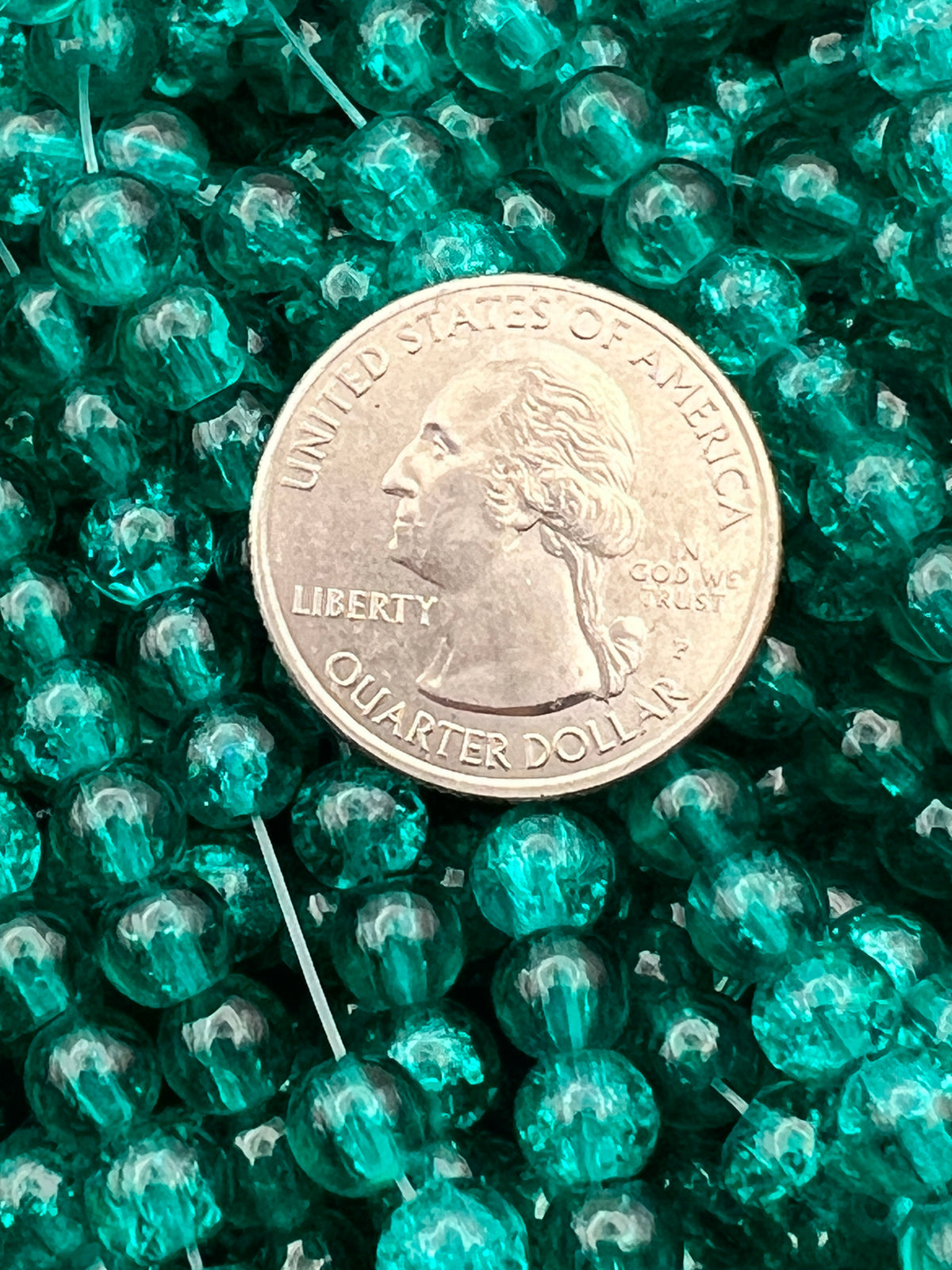 Teal 6mm crackle glass beads shown next to a US quarter for size comparison.
