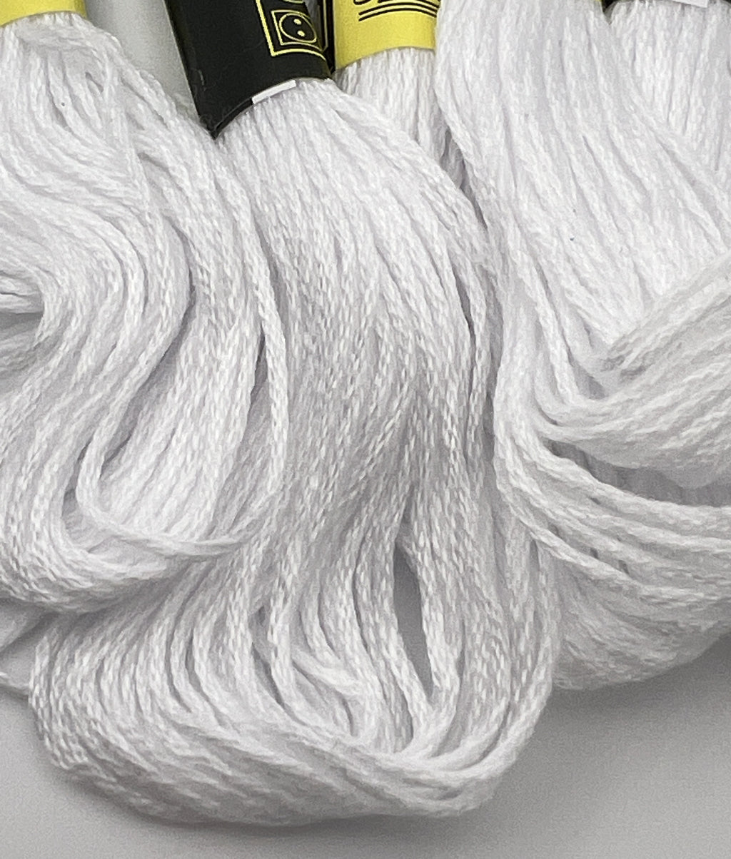 Close-up of five skeins of 1.4mm white 6-ply cotton embroidery thread.