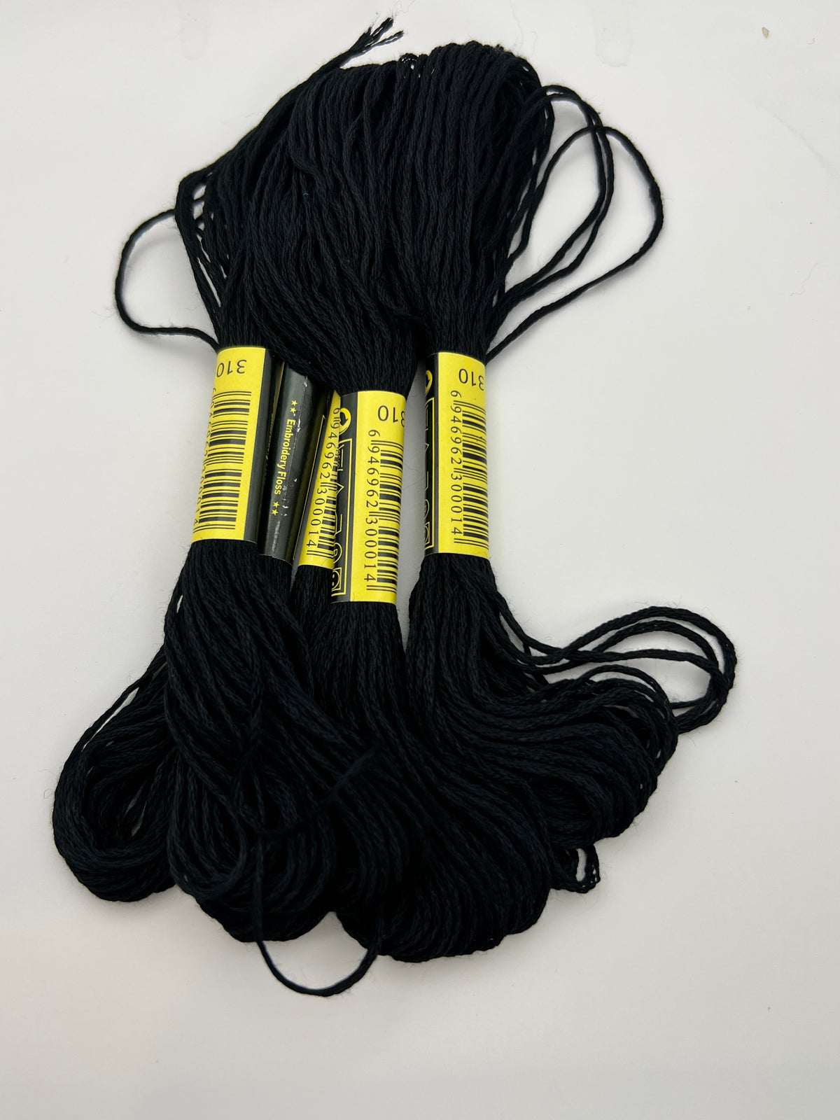 Five skeins of black 1.4mm 6-ply embroidery thread with yellow labels showing color code 310.