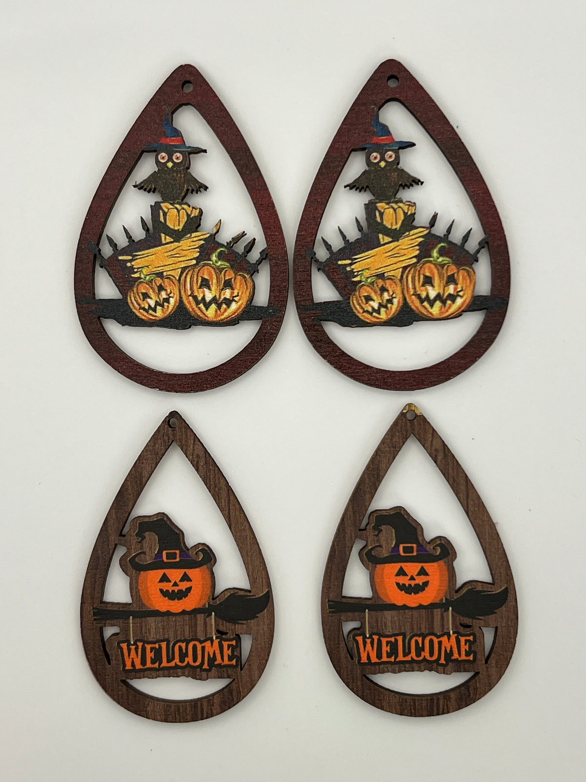 Four teardrop-shaped wood pendants with Halloween designs: owls, pumpkins, and witch hats.