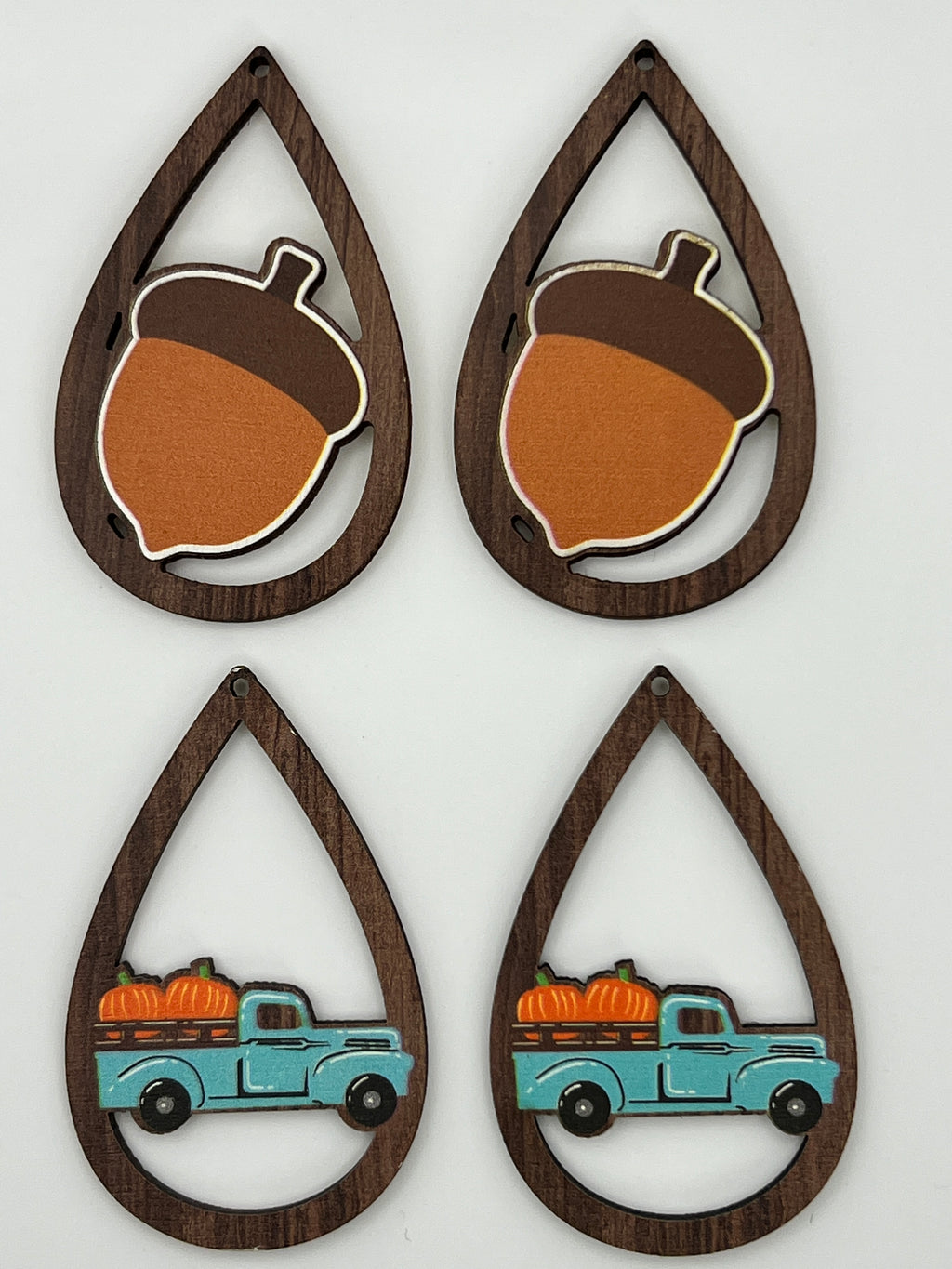 Four teardrop-shaped wood pendants featuring printed acorn and blue pumpkin truck designs.