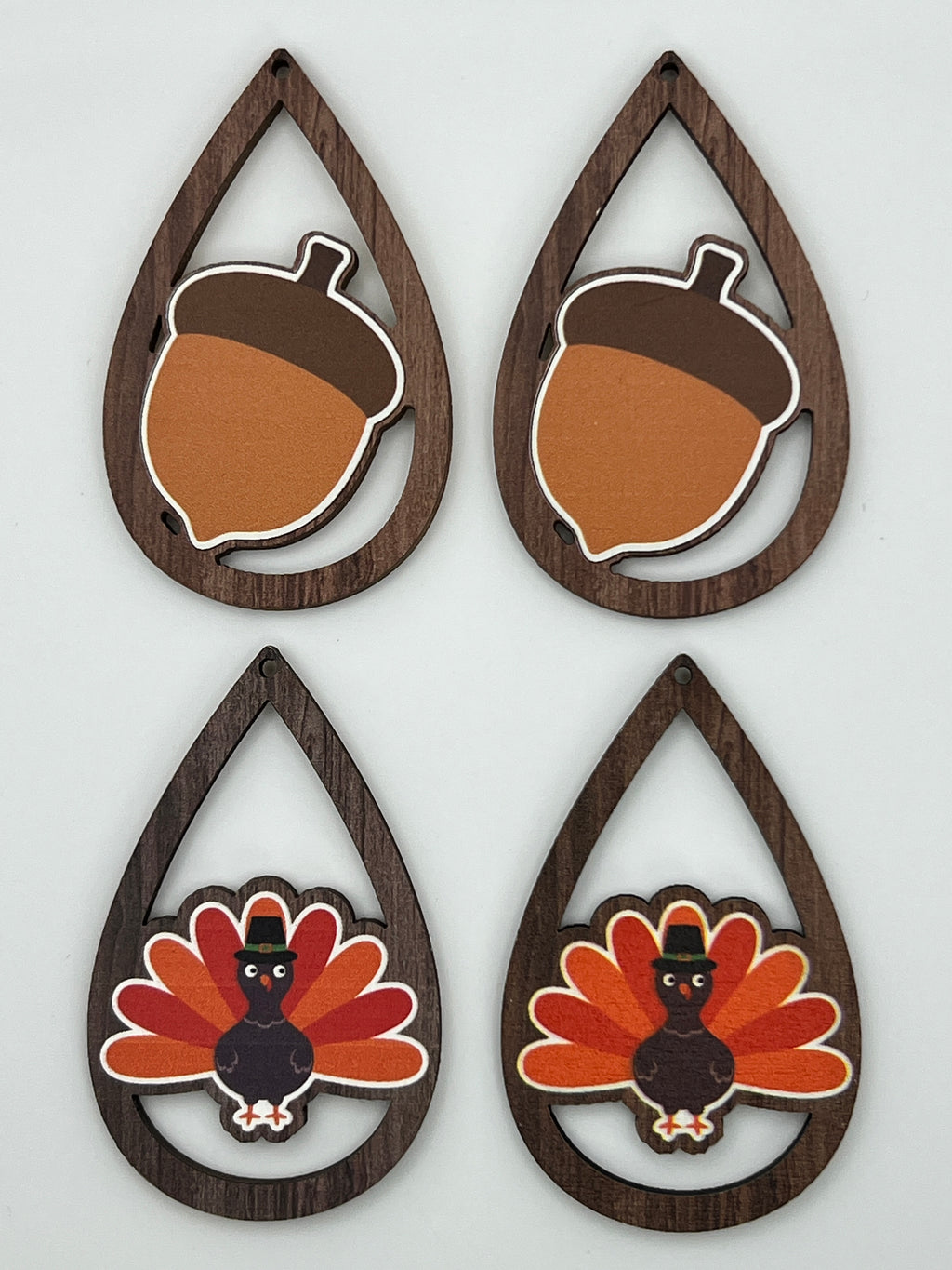 Four teardrop-shaped wood pendants featuring printed acorn and turkey designs in autumn colors.