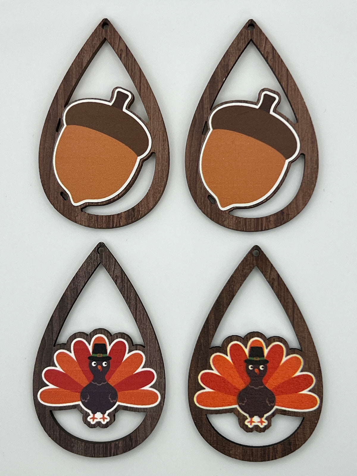 Four teardrop-shaped wood pendants featuring printed acorn and turkey designs in autumn colors.