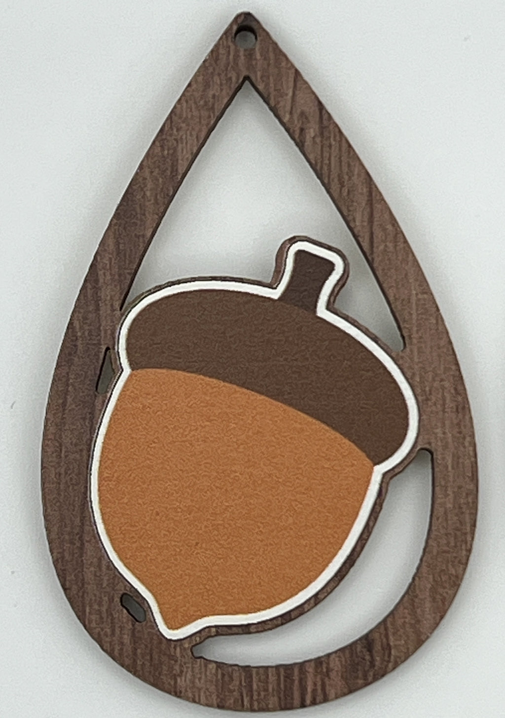 Teardrop-shaped wood earring finding with a dark wood grain frame and a printed acorn center.