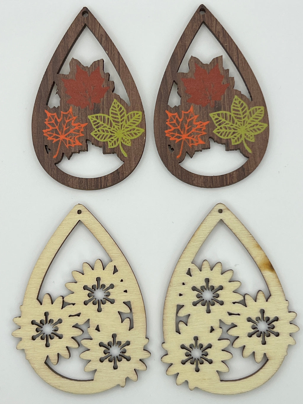 Two pairs of teardrop wood pendants: one with printed fall leaves, one natural blank with flowers.