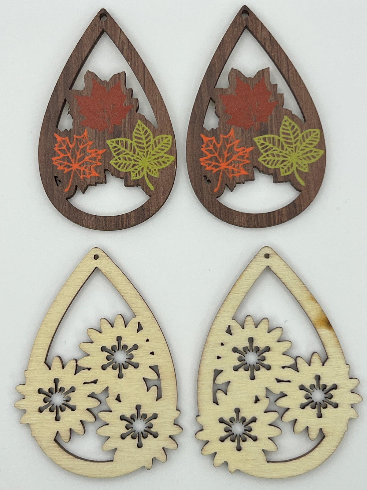 Two pairs of teardrop wood pendants: one with printed fall leaves, one natural blank with flowers.