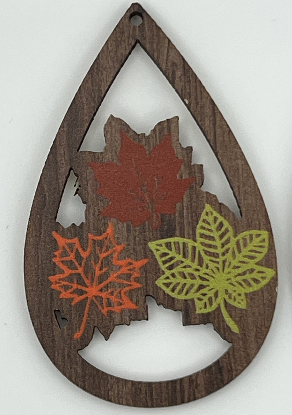 Teardrop-shaped wood pendant featuring three printed autumn leaves in red, orange, and green.
