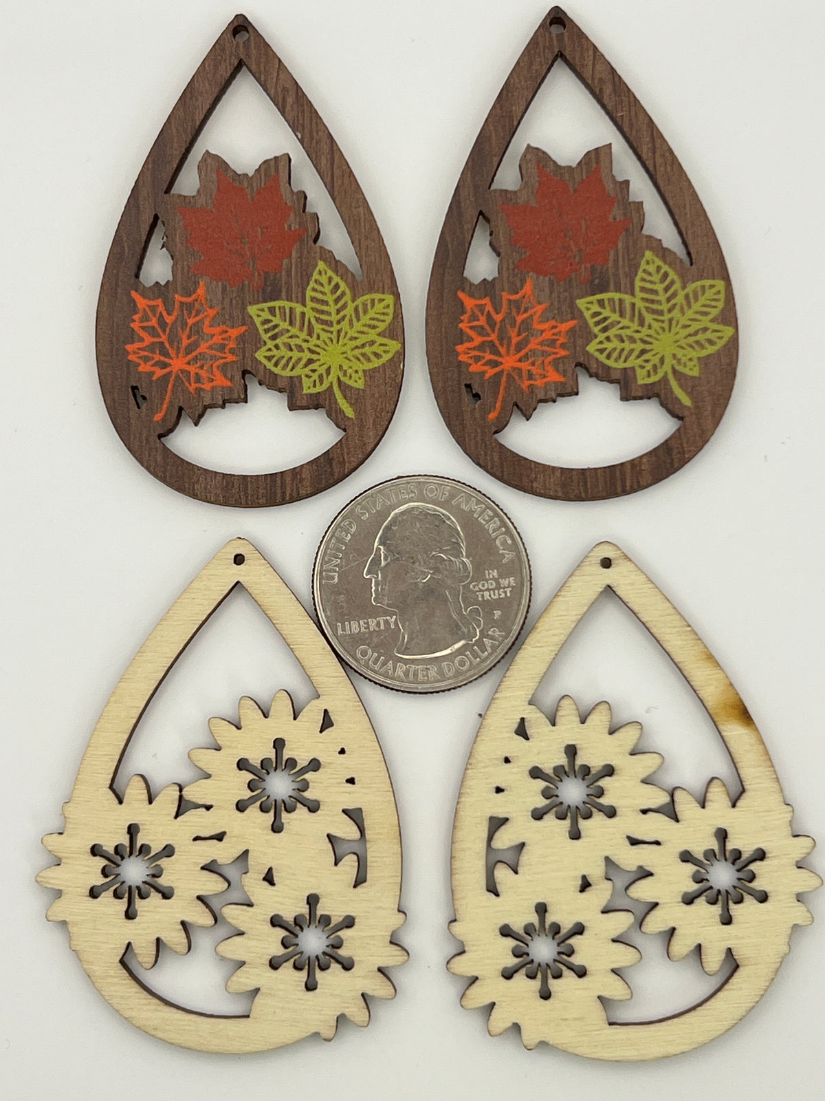 Four teardrop wood pendants: two with printed fall leaves and two natural blank floral cut-outs.