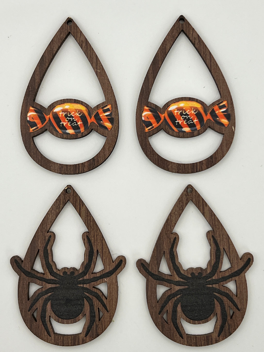 Four teardrop-shaped wood pendants: two with orange candy and two with black spiders.