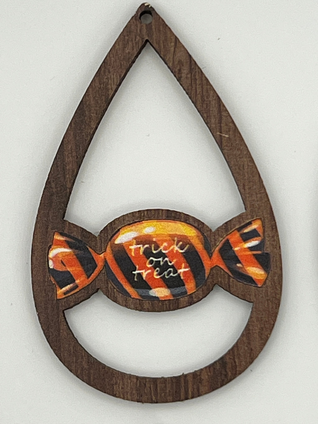 Teardrop-shaped wood pendant with a center candy design featuring the text "trick or treat".