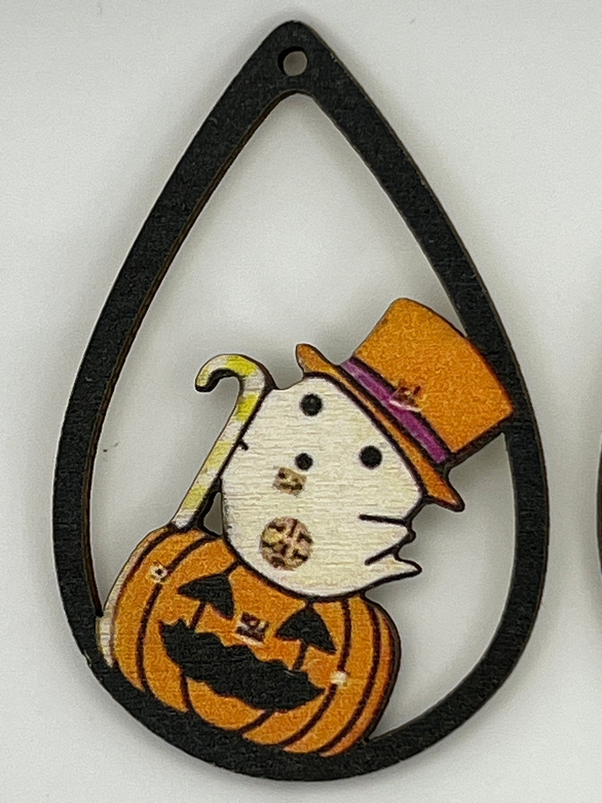 Teardrop-shaped wood earring finding featuring a ghost in a top hat popping out of a pumpkin.