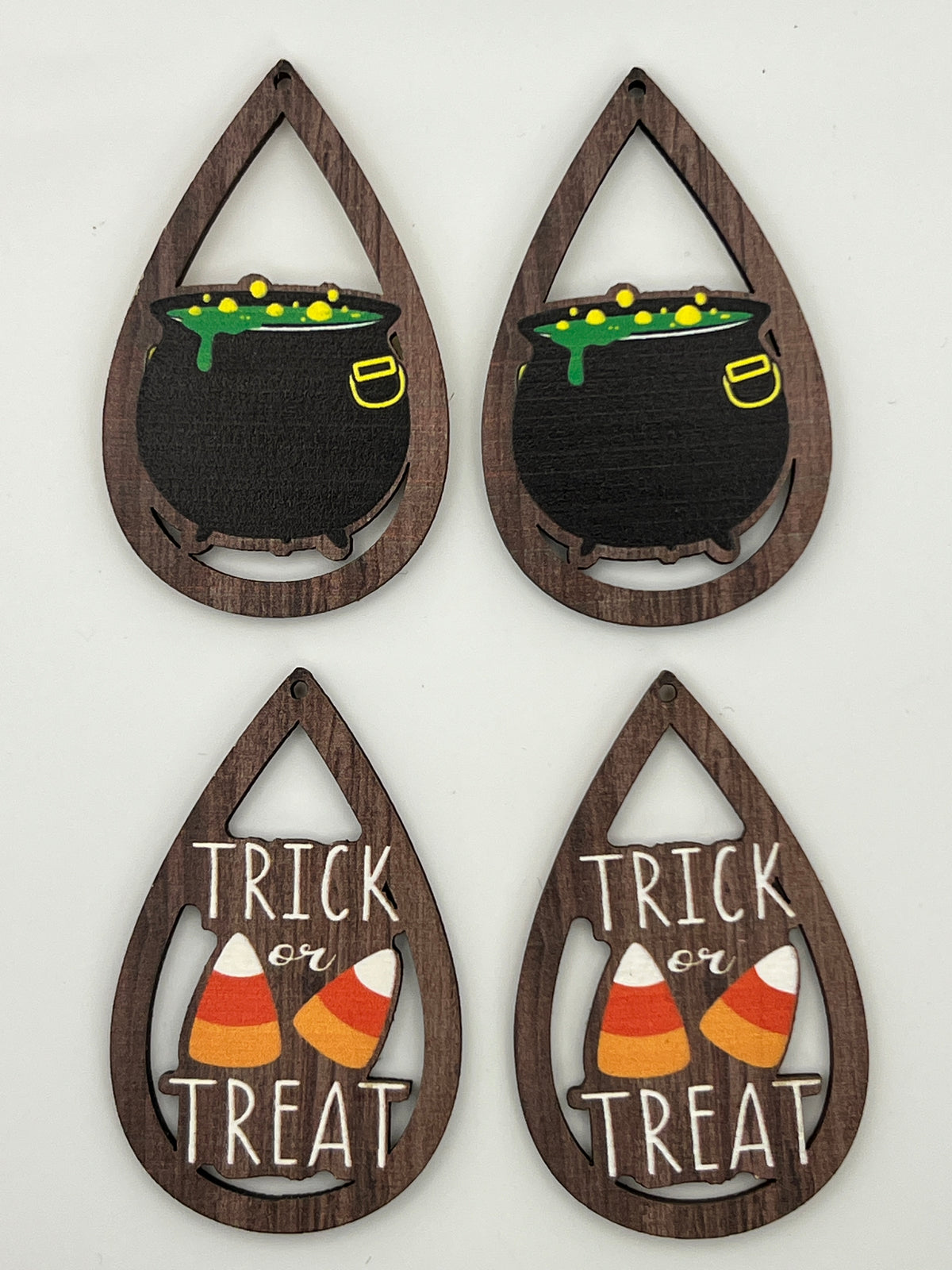 Four teardrop-shaped wood pendants: two with bubbling cauldrons and two with Trick or Treat designs.