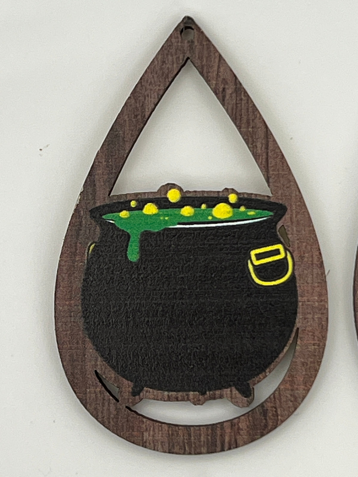 Teardrop-shaped wood earring finding featuring a black cauldron with bubbling green liquid.