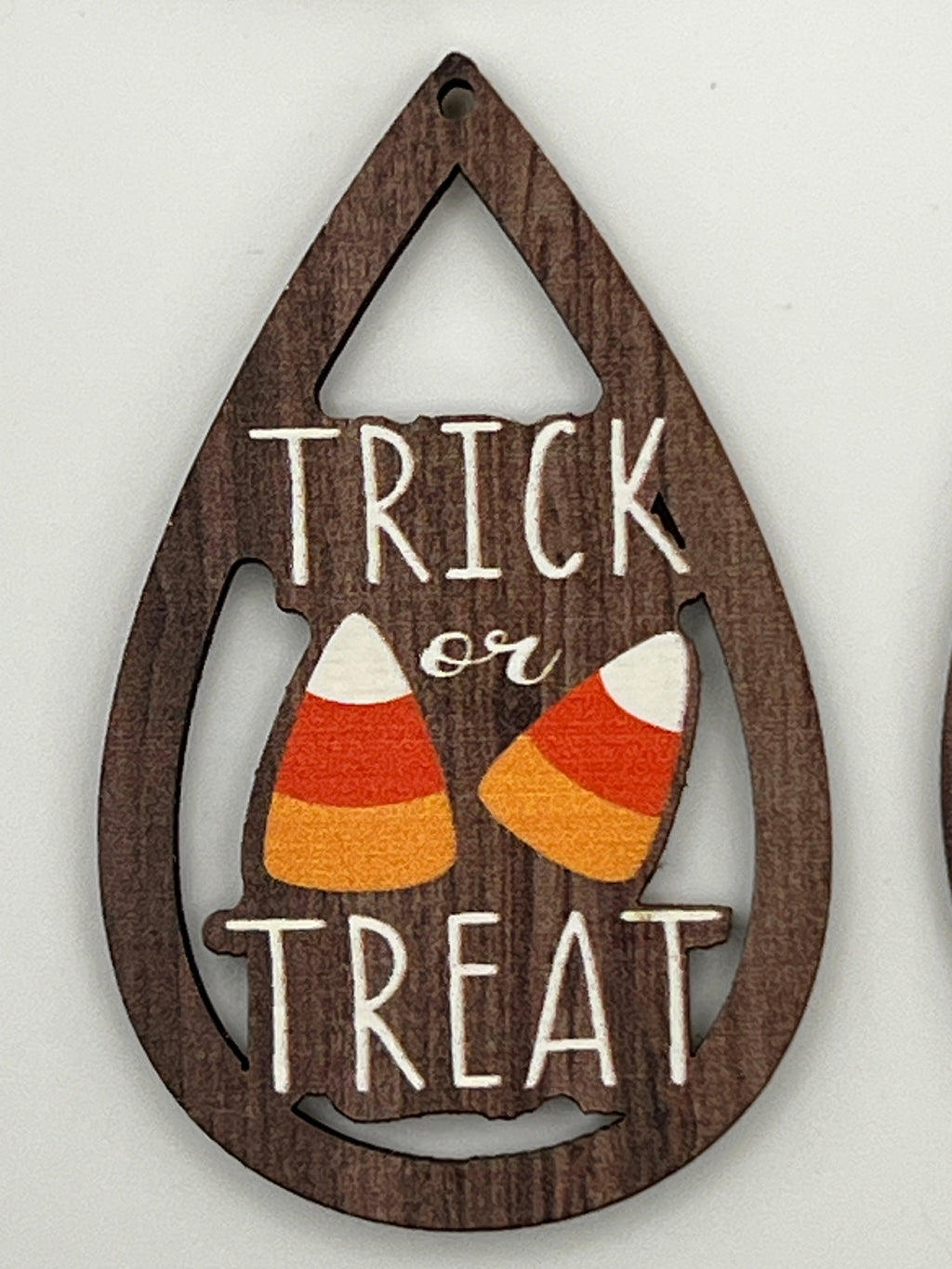 Teardrop-shaped wood pendant with 'TRICK or TREAT' text and two candy corn illustrations.