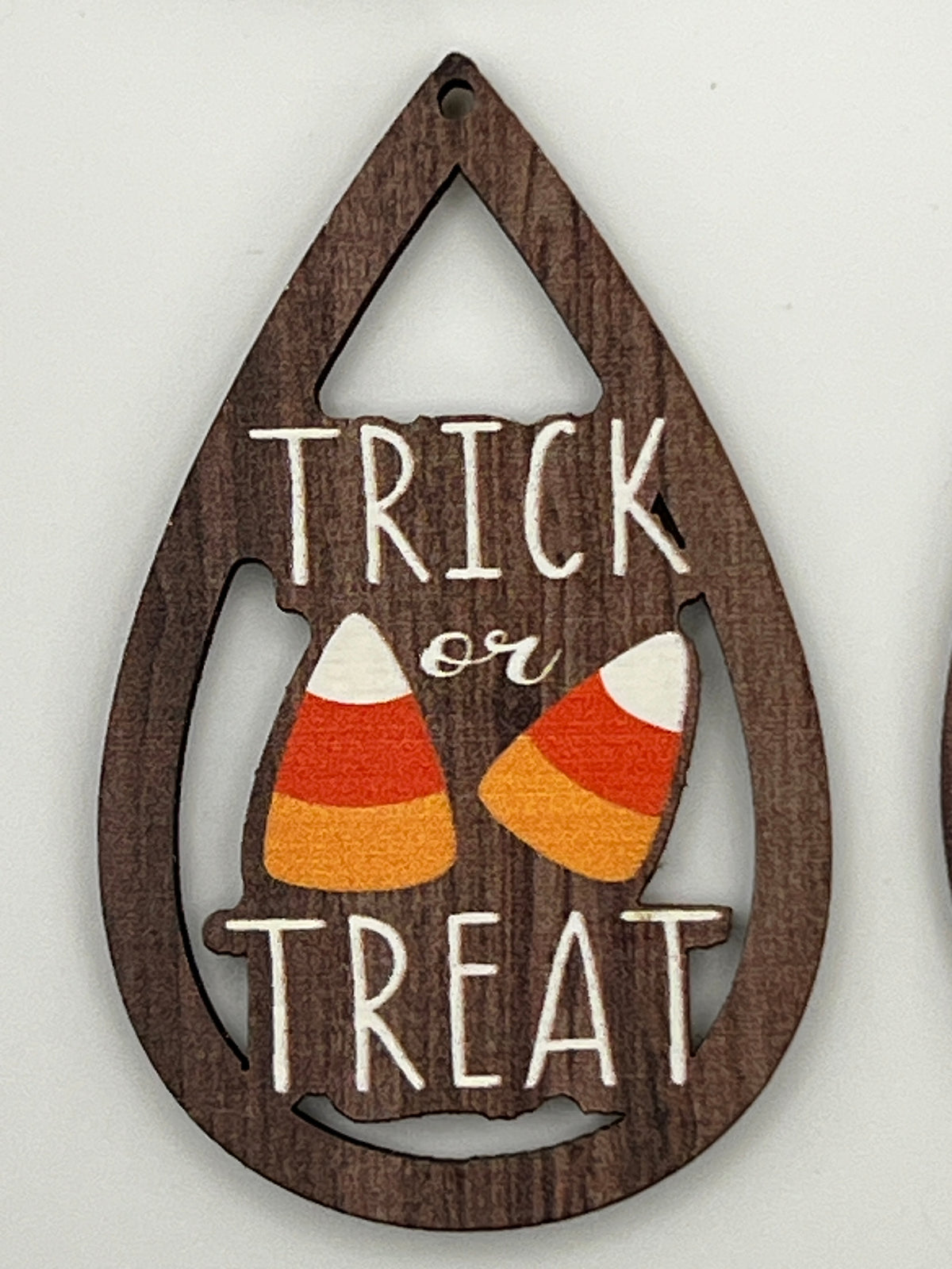 Teardrop-shaped wood pendant with 'TRICK or TREAT' text and two candy corn illustrations.