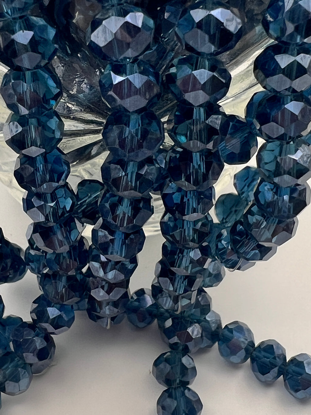 Close-up of faceted 8x6mm marine blue glass rondelle beads with a pearl luster finish.