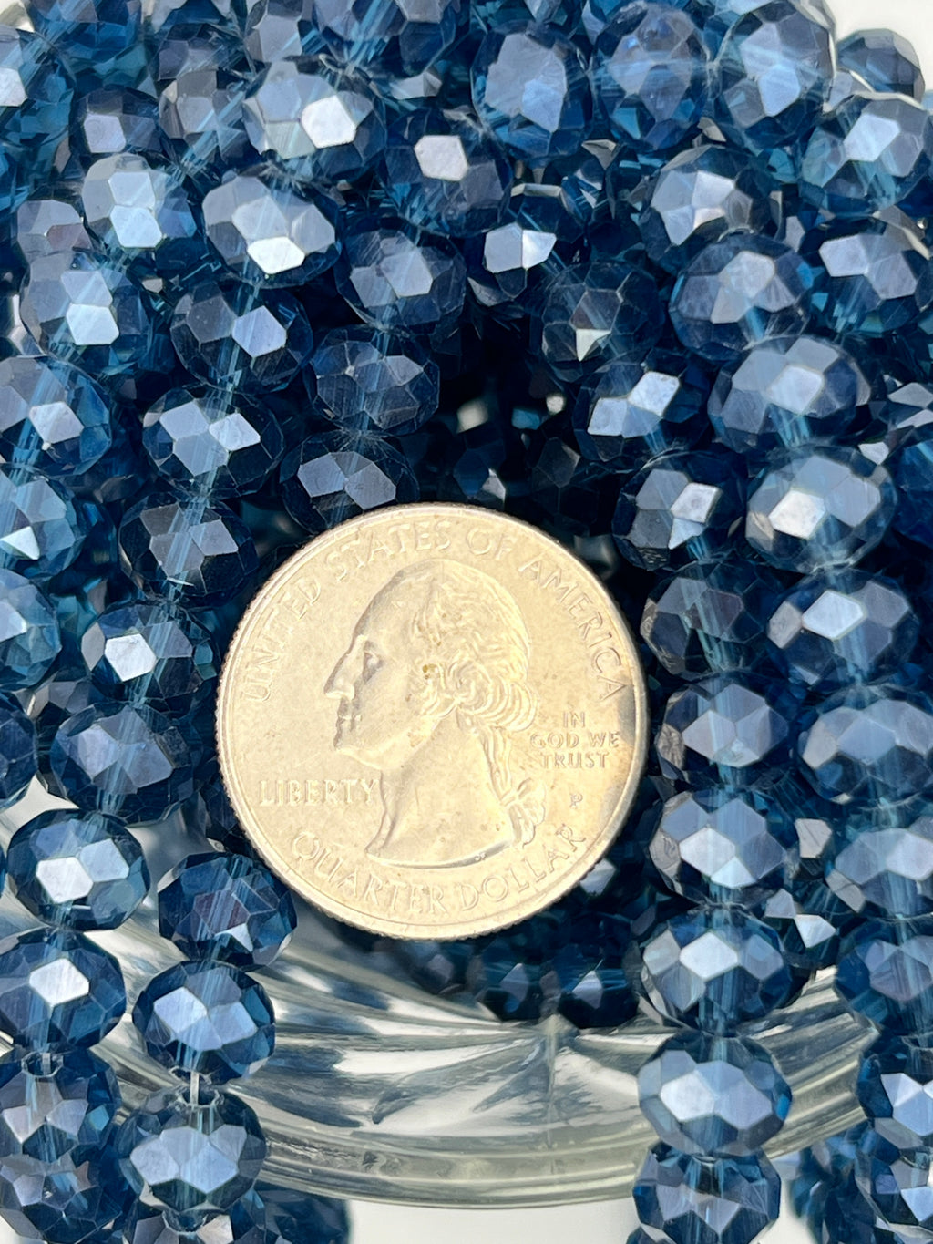 Marine blue 8x6mm faceted glass rondelle beads with pearl luster finish next to a US quarter.
