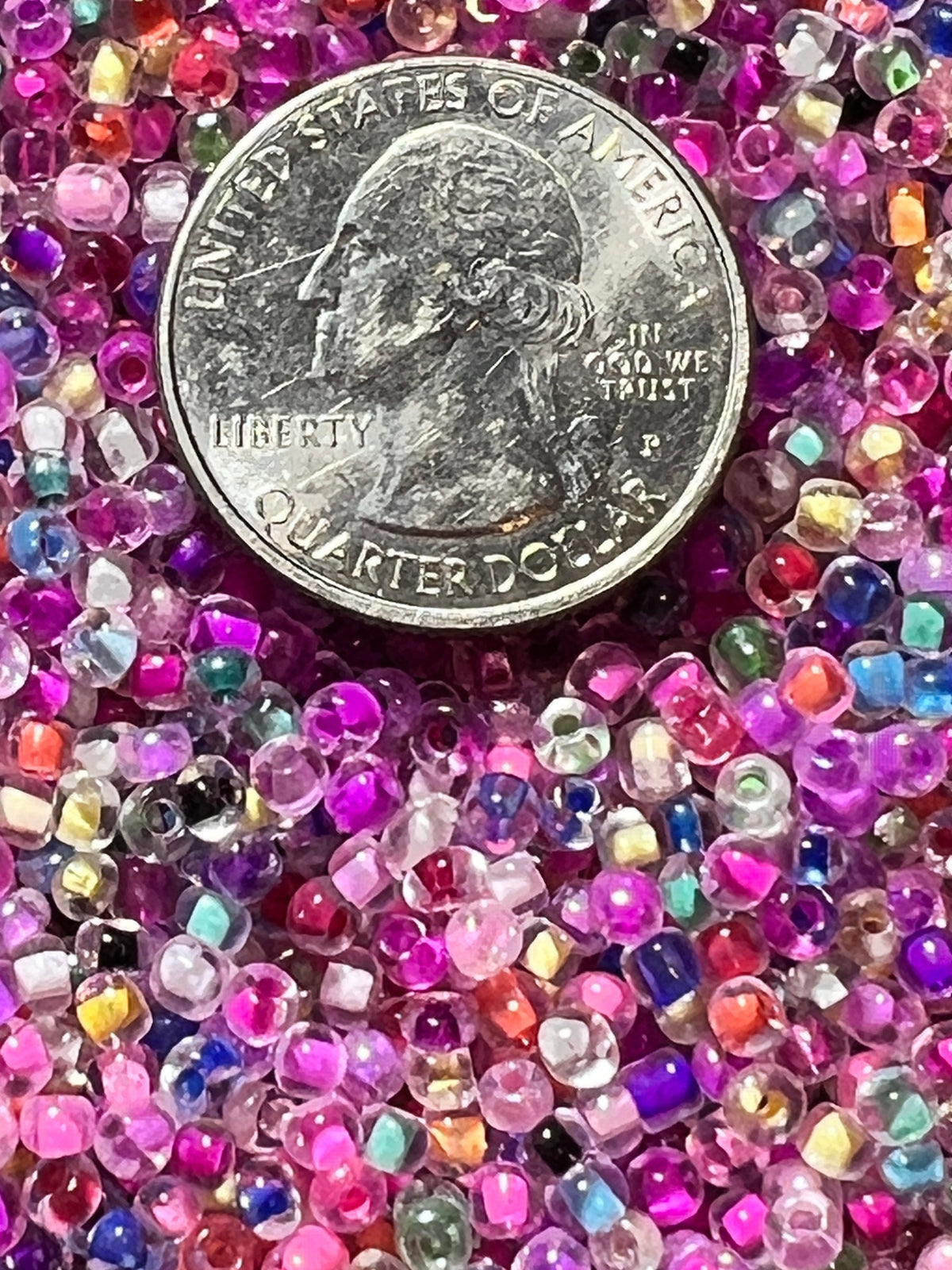 Mixed color 8/0 glass seed beads with internal coloring shown next to a US quarter for scale.