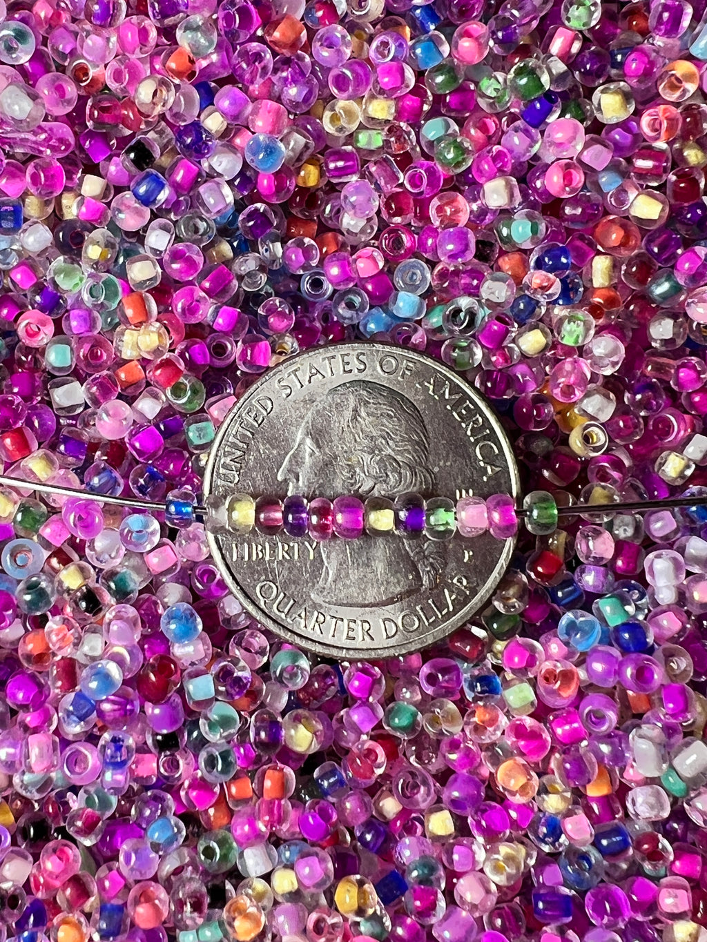 Mixed color 8/0 glass seed beads with internal coloring shown next to a US quarter for scale.