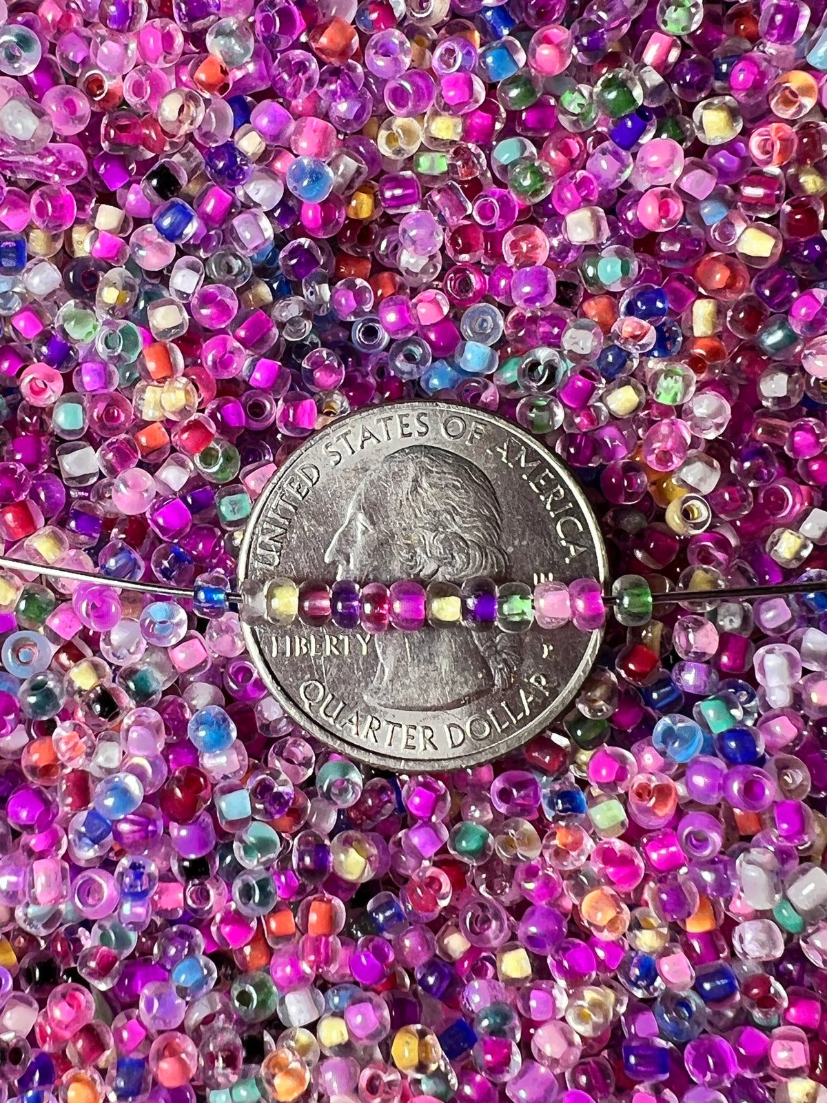 Mixed color 8/0 glass seed beads with internal coloring shown next to a US quarter for scale.