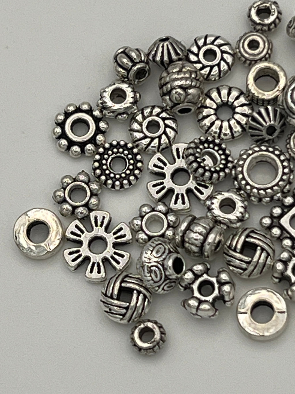 A collection of 50 mixed Tibetan style spacer beads in various shapes and sizes.