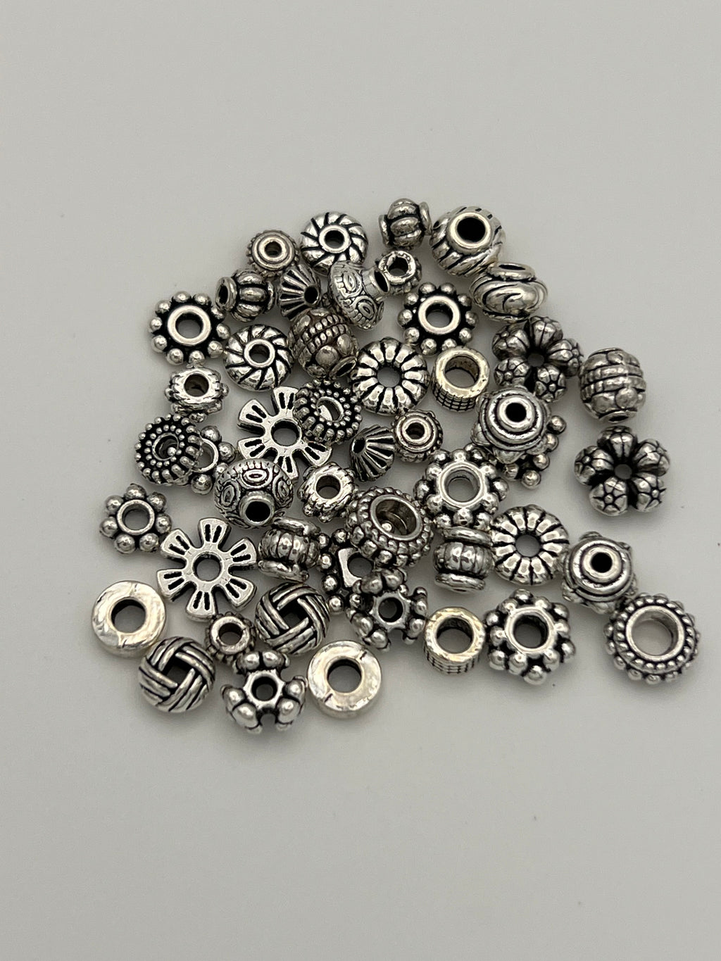 A pile of 50 mixed Tibetan style spacer beads in various shapes and sizes.