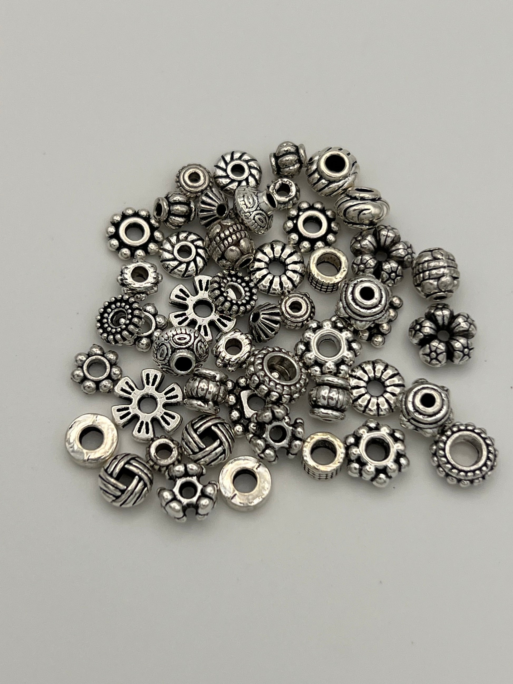 A pile of 50 mixed Tibetan style spacer beads in various shapes and sizes.